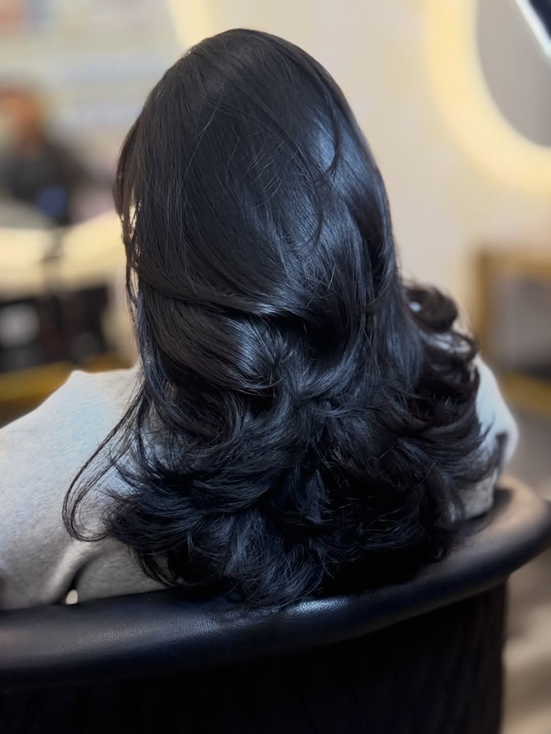 Back view of a customer's glossy black layered hairstyle